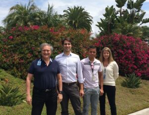 A group of scientists standing outside in front of flowering bushes.