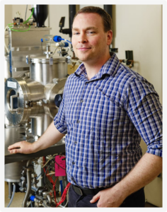 A scientist stands in front of machinery